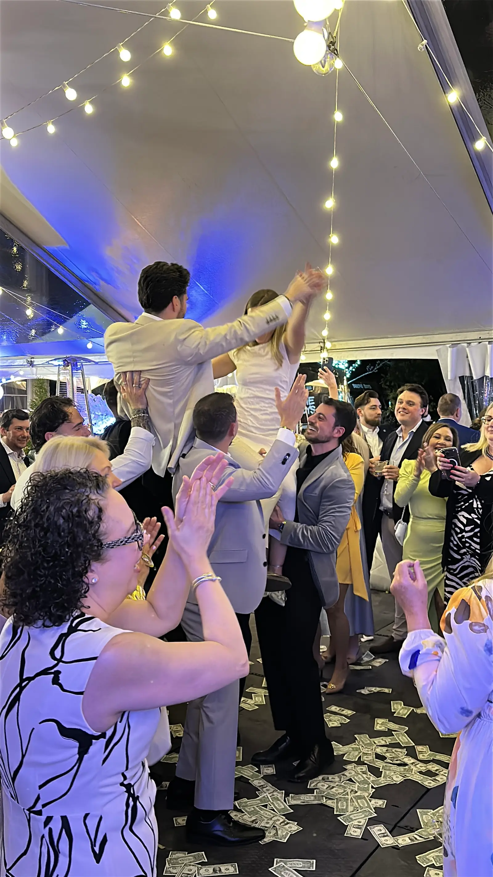 Guests lifting the newlyweds on chairs during the hora at a Greek wedding